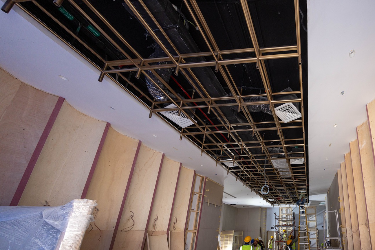 Pearl House By Imtiaz View of a construction site featuring a suspended ceiling frame, wooden walls, and workers in hard hats.